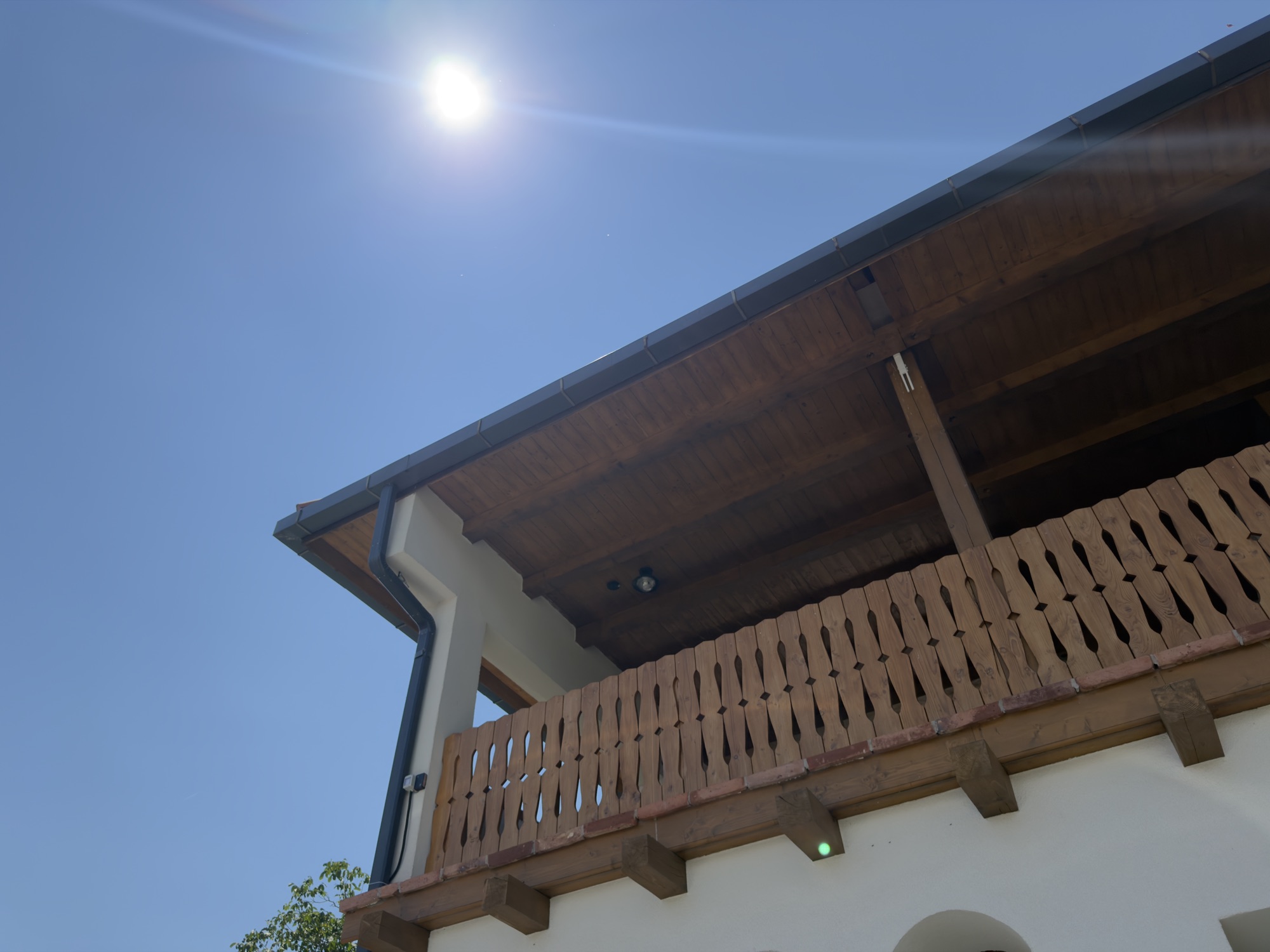 Balconul din lemn al pensiunii pe cerul senin al Gorjului
